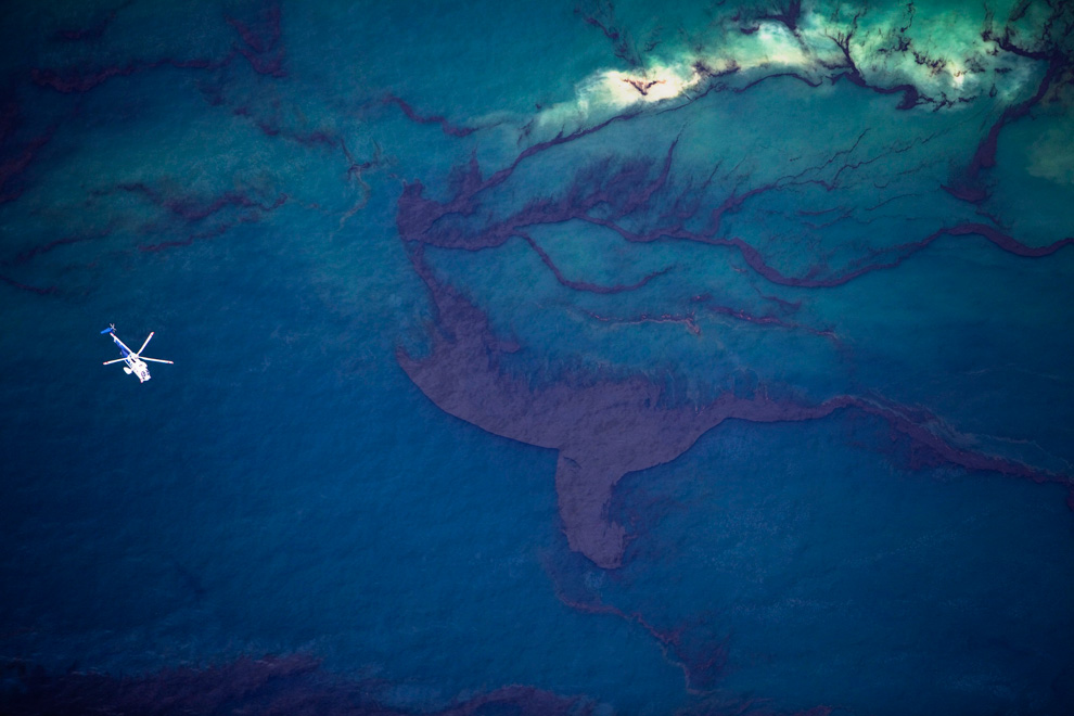 A helicopter flies over surface oil slick, Gulf of Mexico